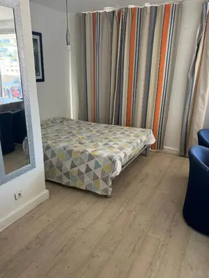 a bed in a room with curtains and a mirror at Apparemment proche de la mer in Cannes