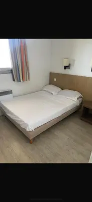 a white bed in a room with a window at Apparemment proche de la mer in Cannes