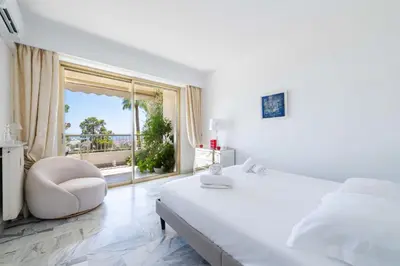 a bedroom with a white bed and a chair and a window at Spacious 1-Br with Sea View Residence with Pool Cannes in Cannes