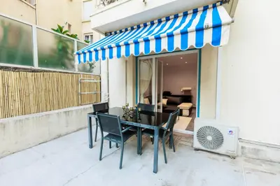 a table with chairs and a blue and white awning at Family Flat Cannes Centre in Cannes