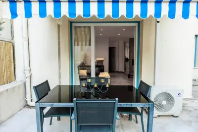 a dining room table with chairs and a blue awning at Family Flat Cannes Centre in Cannes