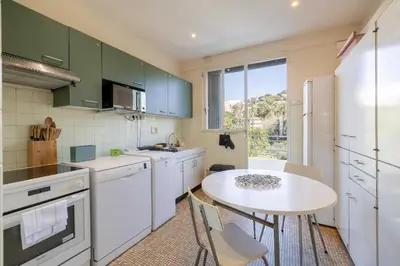 a kitchen with green cabinets and a small table with chairs at Flat -2BDR-4P - SEA VIEW in Cannes
