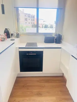a kitchen with white cabinets and a black dishwasher at Cannes Croix des Gardes in Cannes