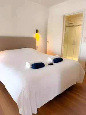 a white bed with two blue pillows on it at Le Noé By ApiRent #Climatisation #Wifi #Balcon in Cannes