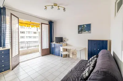 a living room with a couch and a desk and a table at LE BRISTOL avec balcon au calme en centre-ville in Cannes