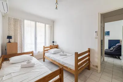 a bedroom with two beds and a window at LE BRISTOL avec balcon au calme en centre-ville in Cannes