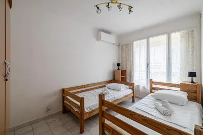 a bedroom with two beds and a window at LE BRISTOL avec balcon au calme en centre-ville in Cannes