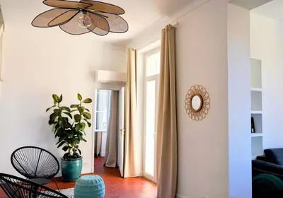 a living room with a ceiling fan and a plant at Villa de la Roche - Spacieux appartement bourgeois in Cannes