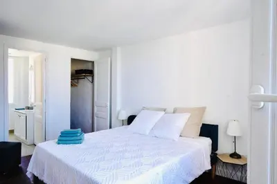 a white bedroom with a white bed with a blue blanket at Villa de la Roche - Spacieux appartement bourgeois in Cannes