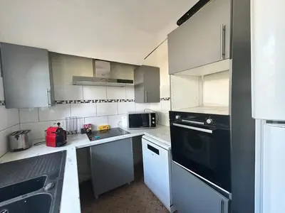a kitchen with white cabinets and black appliances at Maison provençale in Le Cannet