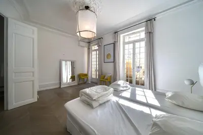 a white bedroom with two beds and a large window at REF 1412 - Cannes Center - Apartment for rent in Cannes