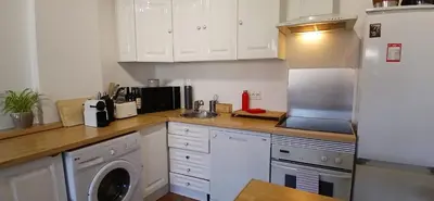 a kitchen with white cabinets and a washer at Bel appartement central 2 chambres in Cannes