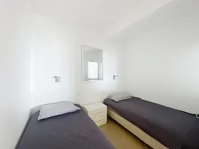 two beds in a white room with a window at Bright one bedroom apartment on La Croisette in Cannes