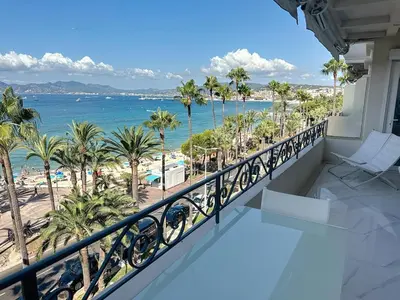 a balcony with a view of the beach and palm trees at Bright one bedroom apartment on La Croisette in Cannes