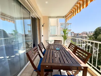 a wooden table and chairs on a balcony with a view at Cannes Azur - SCLS Locations in Cannes