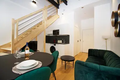 a living room with a table and green chairs at L'Ecrin Festivalier Standing Presta in Cannes