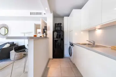 a kitchen with white cabinets and a black refrigerator at 1-Br Garden Apartment with Pool Peaceful Private Parking in Cannes