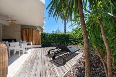 a patio with a table and chairs and palm trees at 1-Br Garden Apartment with Pool Peaceful Private Parking in Cannes