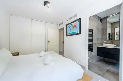 a white bedroom with a large bed and a bathroom at 1-Br Garden Apartment with Pool Peaceful Private Parking in Cannes