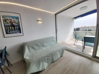 a bedroom with a bed and a balcony with a table at Studio Cannes beautiful sea view in Cannes