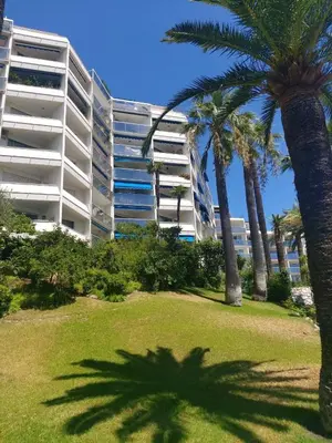a large building with palm trees in front of a park at Studio Cannes beautiful sea view in Cannes