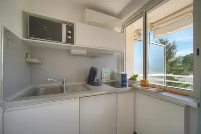 a kitchen with white cabinets and a sink and a window at Tine -Croisette-150M Plage- VCA in Cannes