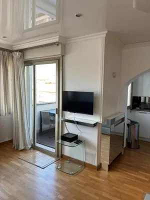 a living room with a television on a wall at Lovely 2 pièces Croisette Martinez in Cannes