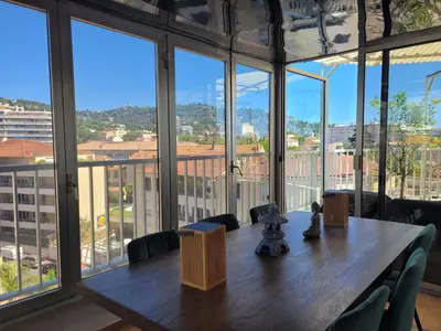 a large room with a wooden table and large windows at Rooftop apartment Cannes center - Parking in Cannes