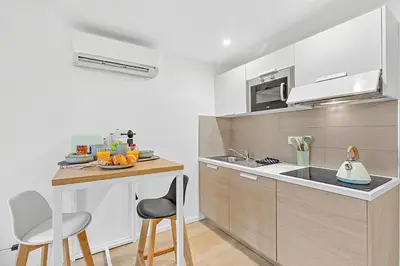 a kitchen with white cabinets and a counter with chairs at Cosy Duplex Mimosa Cannes Center - Happy Rentals in Cannes