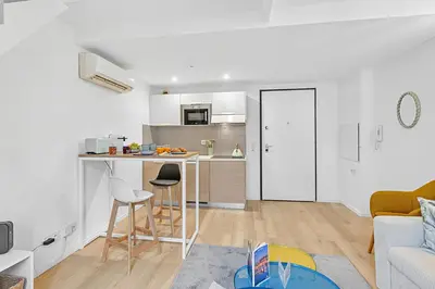 a white living room with a kitchen with a counter at Cosy Duplex Mimosa Cannes Center - Happy Rentals in Cannes