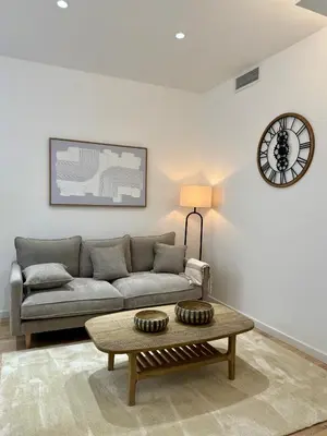 a living room with a couch and a clock on the wall at Lumière by Connexion in Cannes