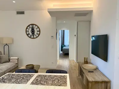 a living room with a couch and a clock on the wall at Lumière by Connexion in Cannes