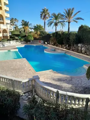 a swimming pool in a resort with palm trees at Cannes plages du Midi Appartements climatisés Bord de mer de 1 à 6 pers, 2 piscines, Parking privatif inclus in Cannes