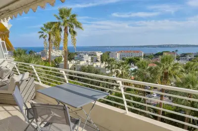 a balcony with a table and chairs and palm trees at Immogroom - 1 Bedroom - Sea view- AC in Cannes