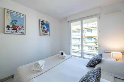 a bedroom with a white bed with a window at Bright One bedroom Apt with Parking and Terrace in Cannes
