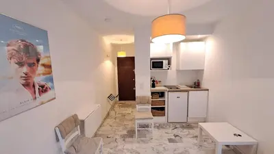 a kitchen and a living room with a table and chairs at Beau studio centre Cannes Maréchal Juin in Cannes