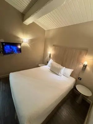 a bedroom with a large white bed and a tv at The Mazet in Cannes