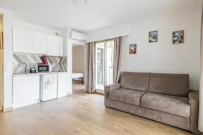 a living room with a couch and a kitchen at LE CHATAIGNIER avec terrasse au calme et central in Cannes