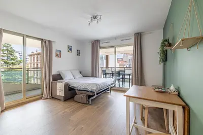 a bedroom with a bed and a large window at LE CHATAIGNIER avec terrasse au calme et central in Cannes