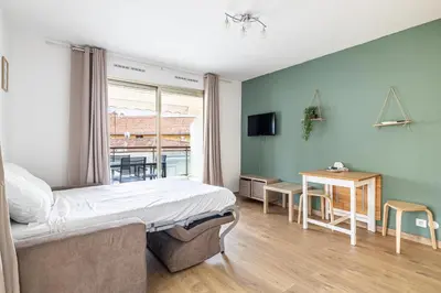 a bedroom with a bed and a desk and a table at LE CHATAIGNIER avec terrasse au calme et central in Cannes