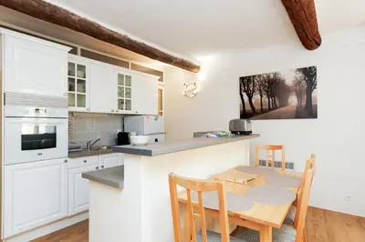 a kitchen with white cabinets and a table and chairs at Le Meynadier Center-Festival-Clim-WiFi in Cannes