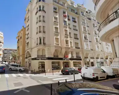 a large building with cars parked in front of it at LE PASTEUR pour tout confort en plein cœur de Cannes in Cannes
