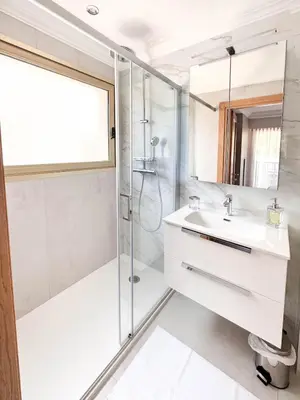 a white bathroom with a shower and a sink at Elegant 2 Br with parking in Cannes