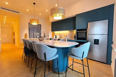 a kitchen with a bar with chairs and a refrigerator at Brand-new 100 sqm apartment with breathtaking panoramic views over Cannes’ in Cannes