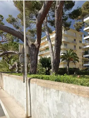 a street light next to a wall with trees and a building at 3-room apartment with sea view in Cannes in Cannes