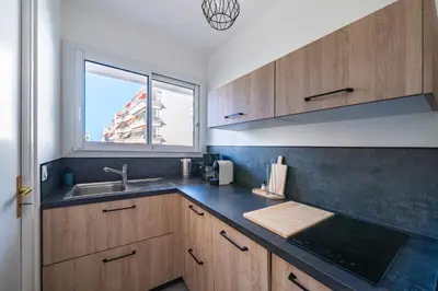 a kitchen with wooden cabinets and a sink and a window at Studio rénové avec grande terrasse - Climatisation - Aperçu mer in Cannes