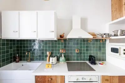 a kitchen with white cabinets and green tiles at Yello YourHostHelper in Cannes