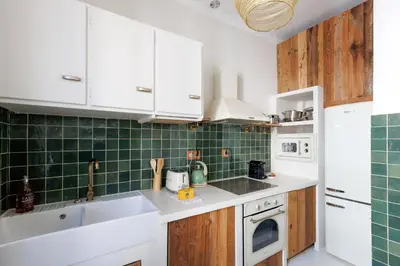 a kitchen with white cabinets and green tiles at Yello YourHostHelper in Cannes