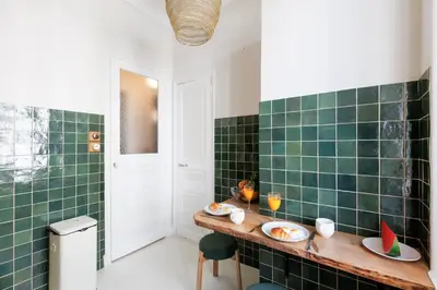 a green tiled kitchen with a table with plates of food at Yello YourHostHelper in Cannes