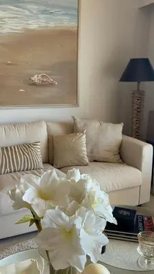 a living room with a couch and a table with white flowers at Stunning 3-Room with Panoramic Views Over Cannes in Le Cannet